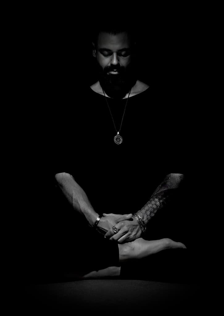 A meditative figure seated in darkness, illuminated softly from above
